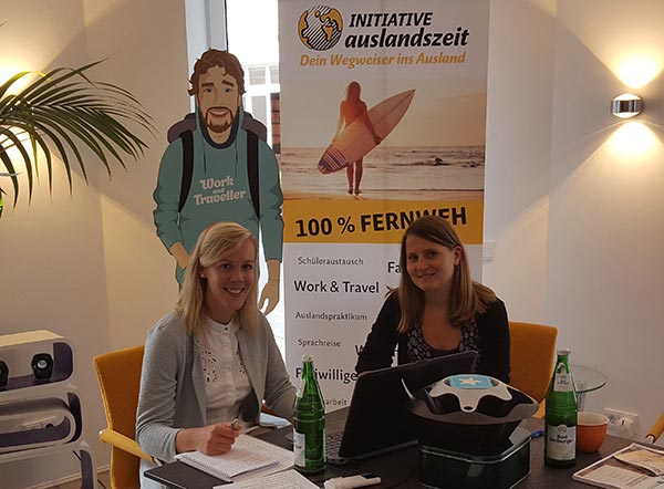 Julia und Jane beim Interview, vor dem Travelbuddy und Initiative auslandszeit Plakat